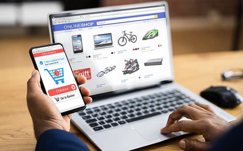 Business owner using virtual merchant processing on laptop and mobile phone to manage online store payments
