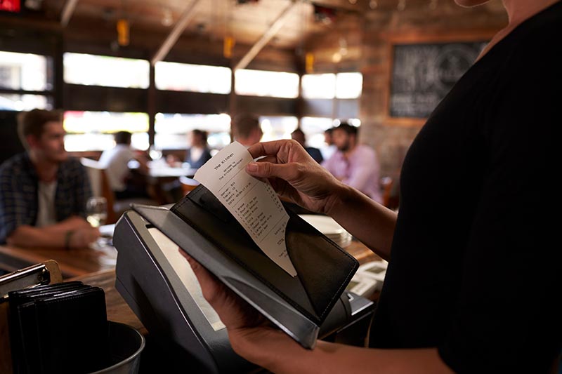 Server preparing the bill at a restaurant to be taken to a table