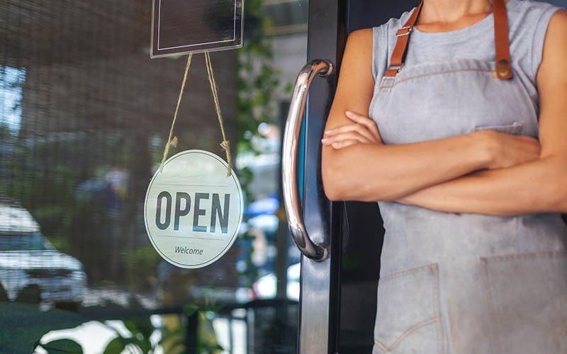 Restaurant Owner in Front of Open Sign