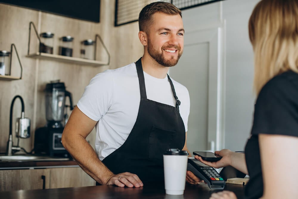 a customer buying coffee with a phone and pos terminal