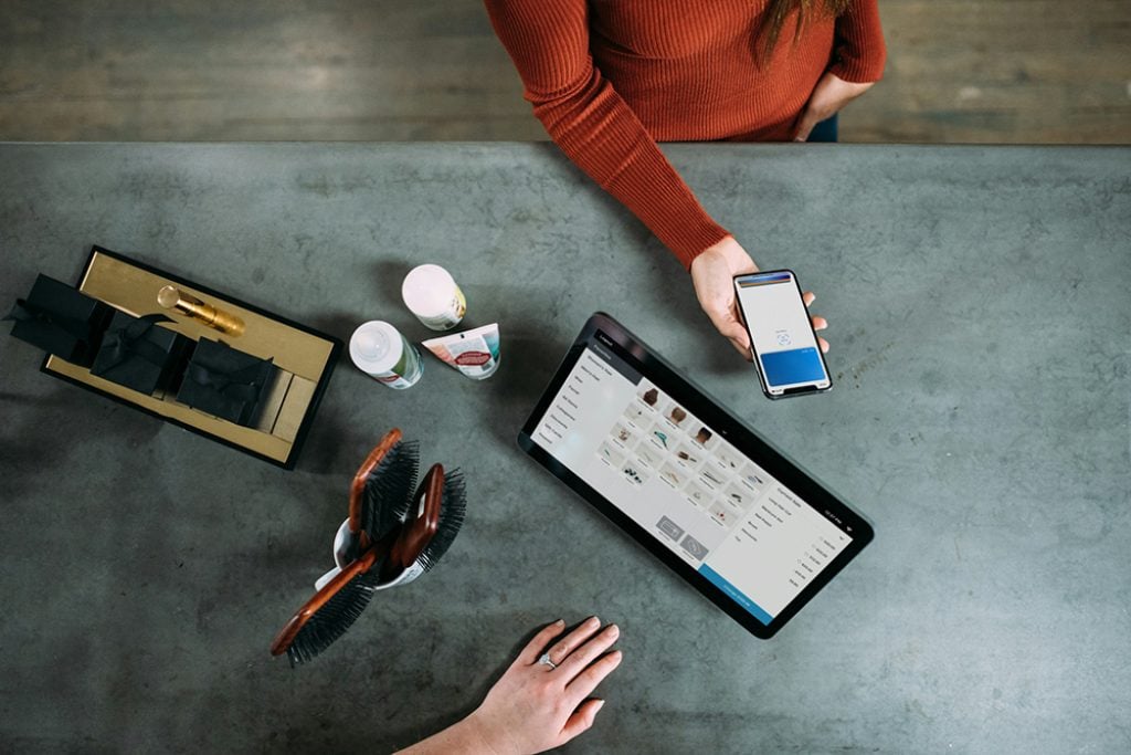 person holding smartphone by POS system