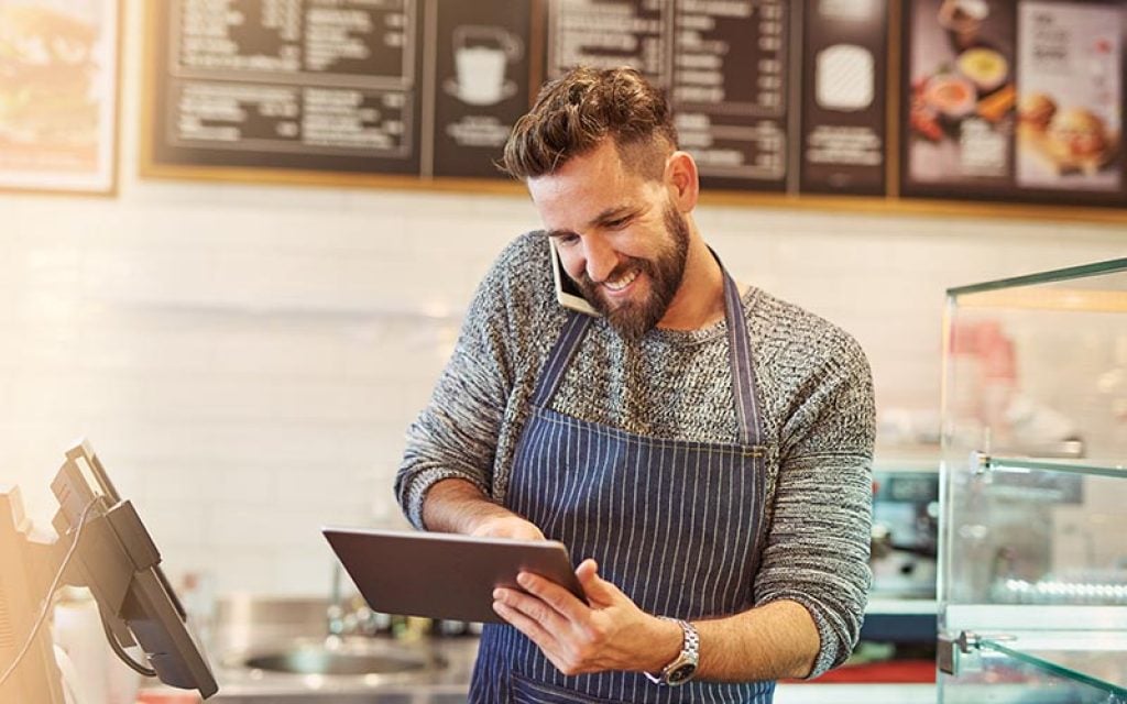 Restaurant owner taking phone order and processing virtual terminal payment on computer