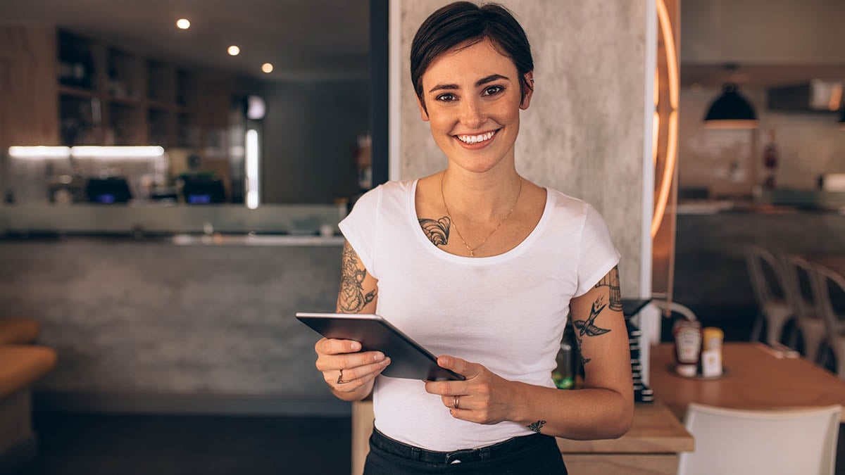 Restaurant owner using tablet to manage digital marketing strategies in modern restaurant setting